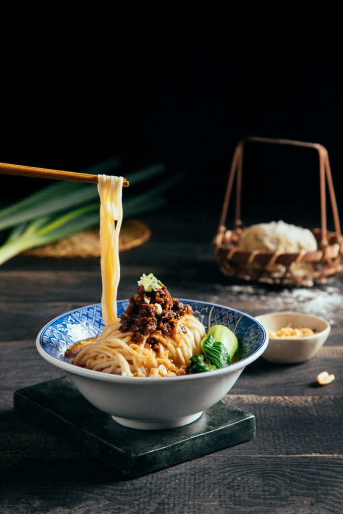 林口亞昕福朋喜來登酒店聚味軒中餐聽主廚特製「牛肉擔擔麵」,改良自傳統四川小吃「擔擔麵」,將乾蔥、蒜與老薑及自製豉椒醬,小火炒香後放入老滷製成的牛肉丁,與杏鮑菇及獨門香辛料一同拌炒,搭配秘制醬汁和胡麻醬,拌入特選拉麵條,香而不膩,辣而不嗆好吃到讓人停不下筷子。(圖/林口亞昕福朋喜來登酒店提供)
