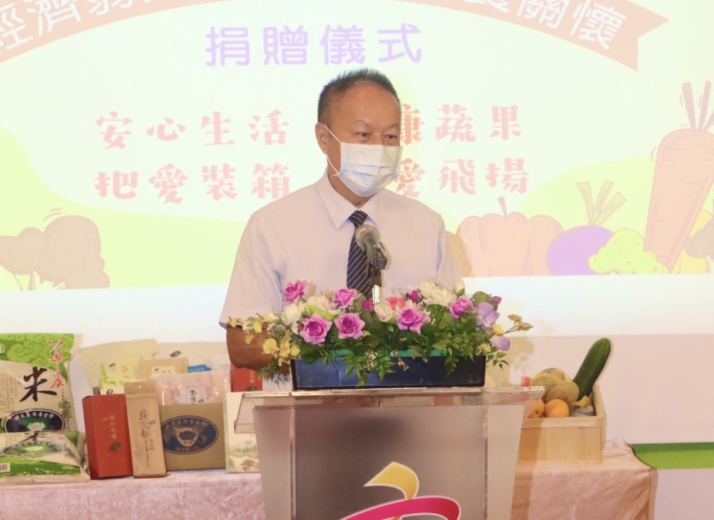 可能是 1 人、站立、花、室內和顯示的文字是「捐贈儀式 安心生活 把愛装箱 康蔬果 蔬 愛飛揚 来」的圖像