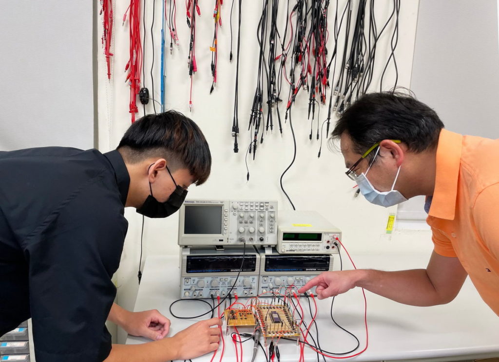 江政達教授與學生徐崇瑜探討晶片在電路板上佈線設計。