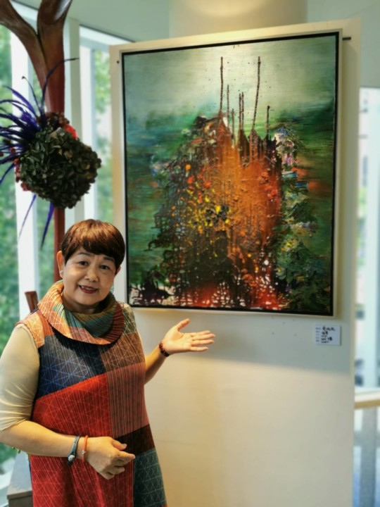 蔡綠綠和她展覽主題油畫作品「跳躍」。(葉志雲攝)