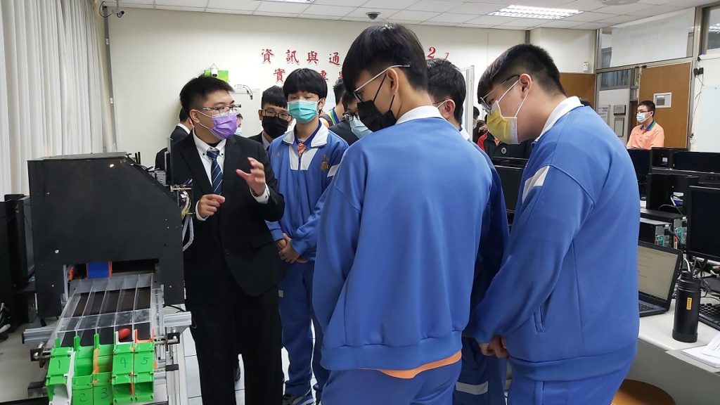 彭彥愷與許育銓現場為參訪的霧峰農工學生導覽,介紹該團隊所製作的「智慧型瑕疪檢測產線」作品功能與特性。(圖/陳惠玲攝影)