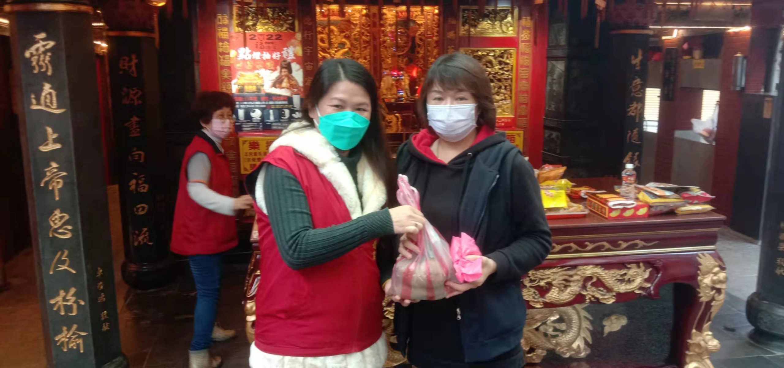 圖片說明：店仔街福德宮管委會總幹事曹雅婷(左)將經神明加持的地瓜分贈給女香客。(記者葉鈞宇攝)