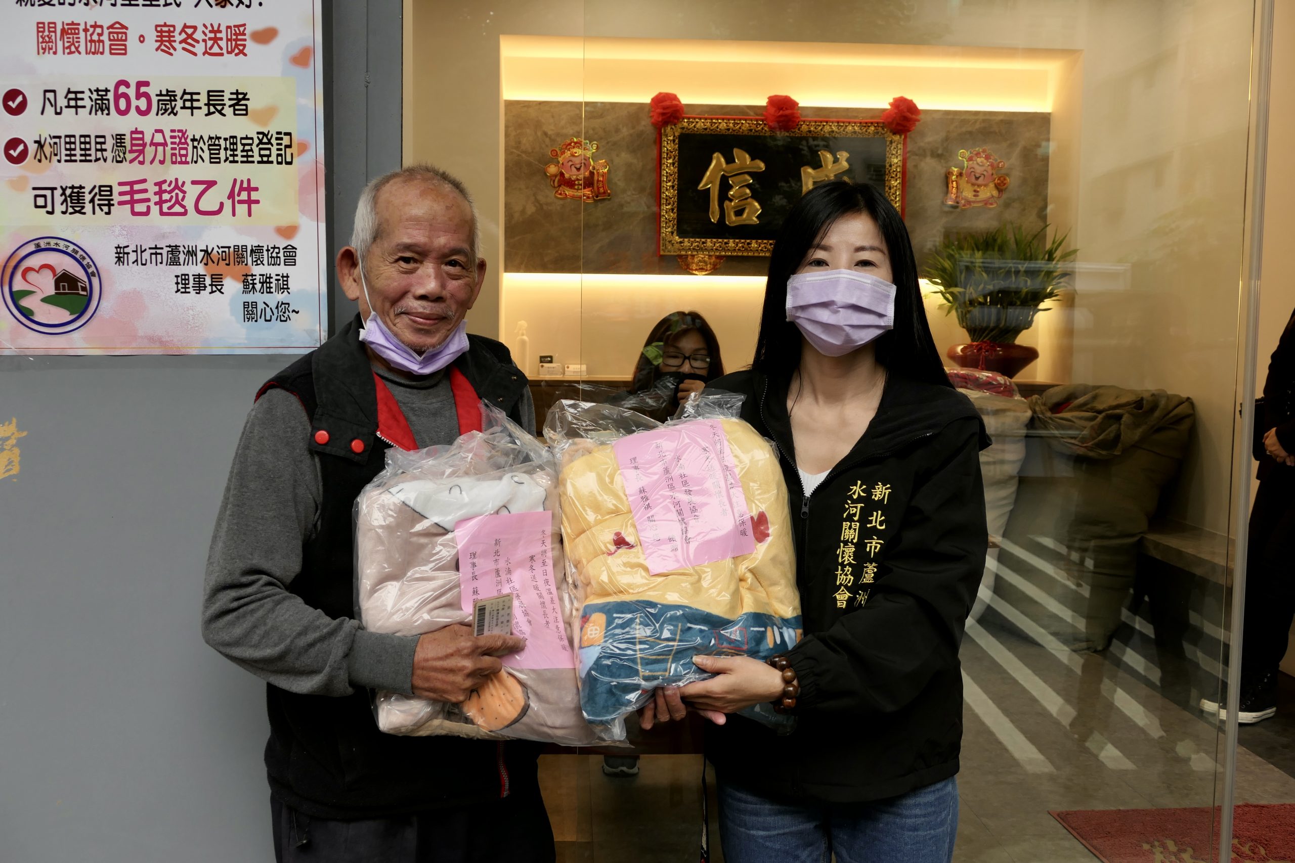 圖片說明:當地居民從蘇理事長(右)手中領到毛毯。(記者朱珈瑩攝)