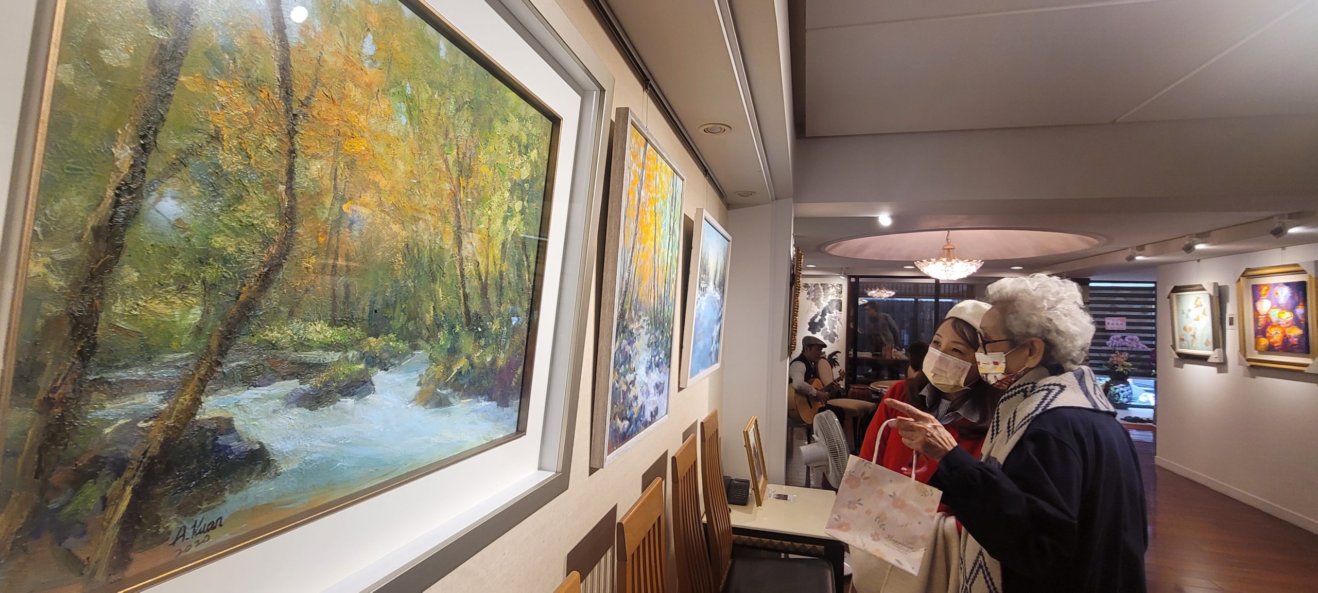 圖片說明:留日的90歲抗癌勵志作家蘇蔡彩秋(人稱蘇媽媽)率先認購畫家關家蘭作品「奧入瀨溪之秋」,關家蘭和蘇媽媽介紹創作理念。(圖/這城以東台北傳愛公益畫展籌委會提供)