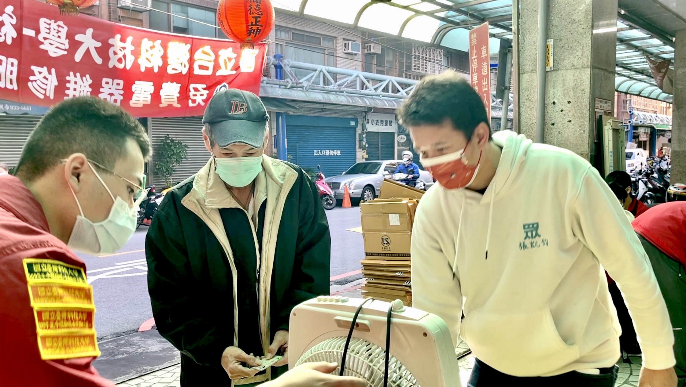 圖片說明:張凱鈞一邊招待前來維修的民眾,一邊發口罩同時宣導防疫。(圖/臺科大社服團提供)