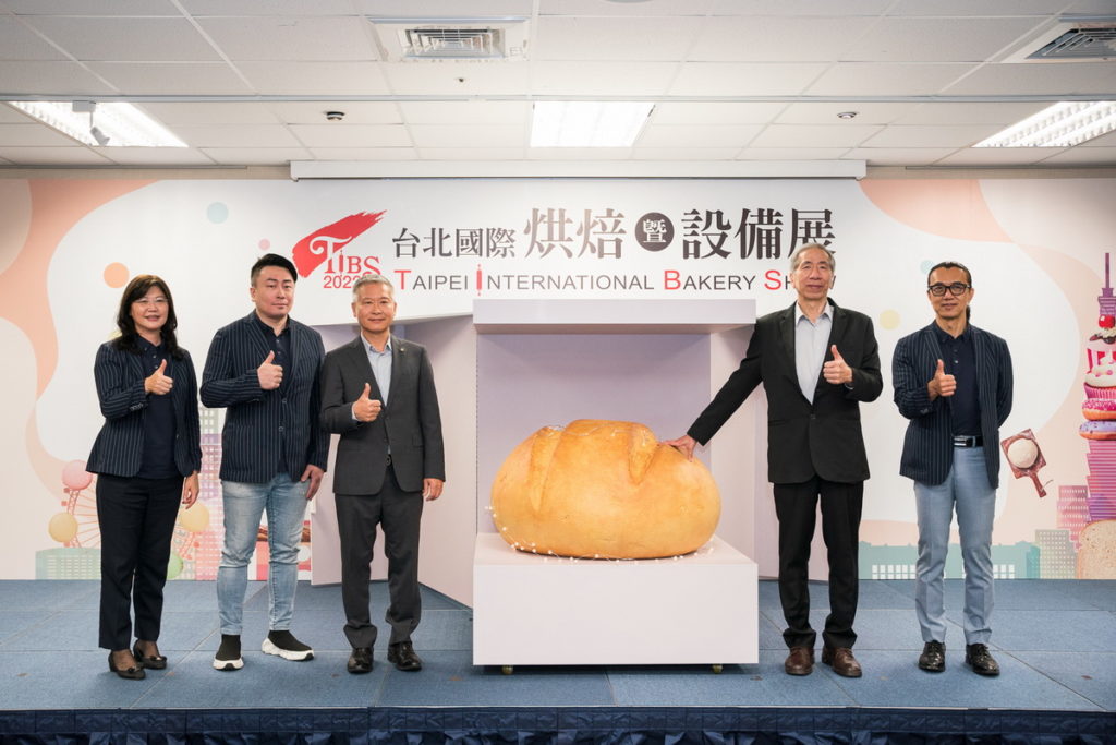 台北國際烘焙暨設備展副主委賴櫻暖(由左至右)、侯景中、展昭國際企業姚晤毅副總經理、台北市糕餅商業同業公會周正訓理事長、台北市糕餅商業同業公會高垂琮名譽理事長共同開箱療癒巨型麵包