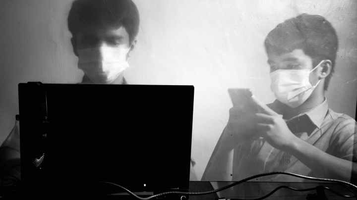 man in medical mask working on laptop and using smartphone