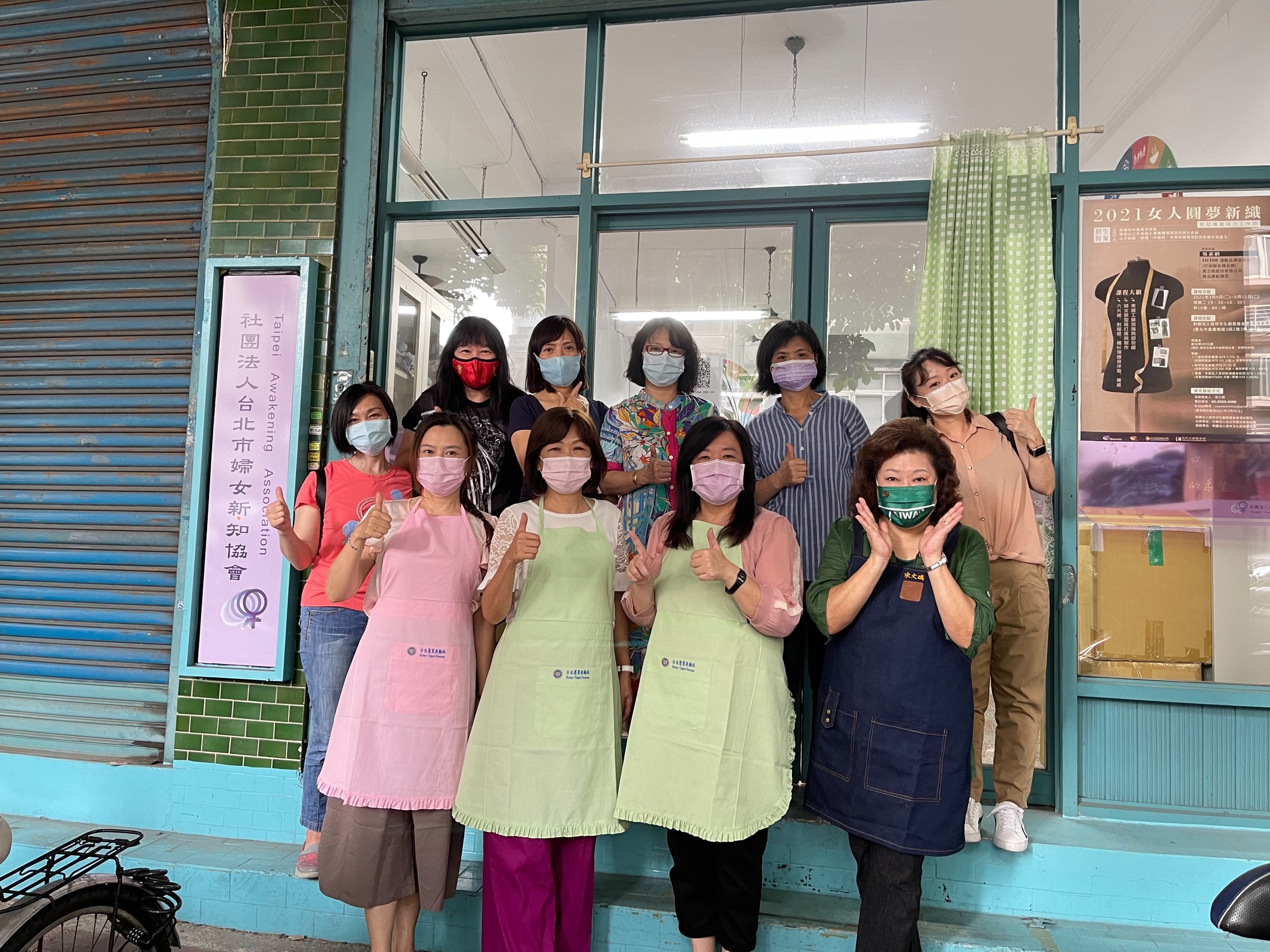 圖片說明:拜訪台北市大同區婦女新知工坊張翠玲主任,委託二度就業婦女製作25週年紀念圍裙、最後到工坊相見歡,並與蔣念祖理事長穿上圍裙,互相加油打氣。(圖/台北蓬萊扶輪社提供)