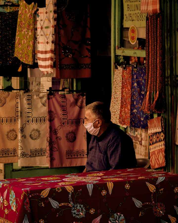 mature ethnic man in bazaar with different textile
