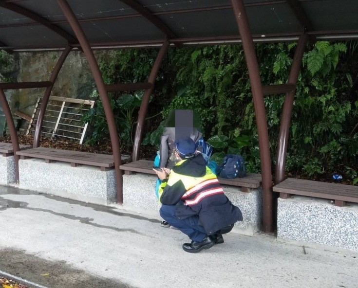 圖片說明:見男童獨坐校門口,基隆市警察局第二分局八斗子分駐所警員羅國倫上前關切。(記者宋紹誠翻攝)