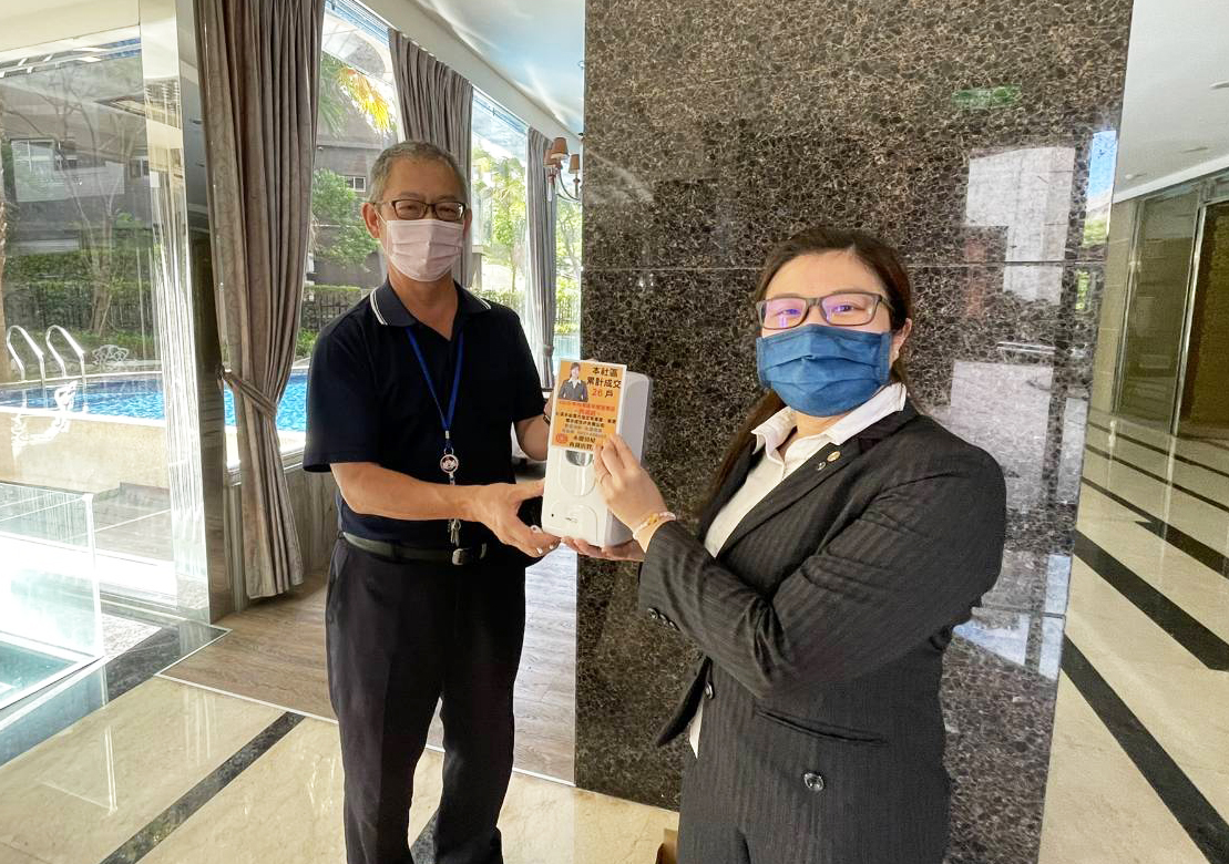 在地服務不因疫情停歇 永慶房屋服務專員為鄰里社區添新色彩 60 永慶房屋貼心服務再升級,贈送感應式酒精消毒機讓住戶們可以消毒雙手。