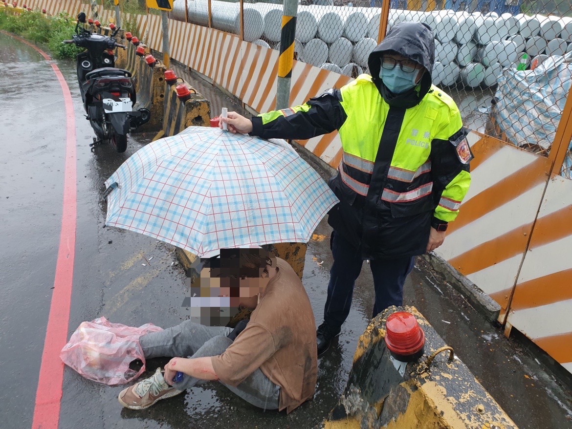 圖片說明:山佳派出所警員何洹、張育齊於滂沱大雨中救助一名車禍受傷民眾。(記者宋紹誠攝)翻