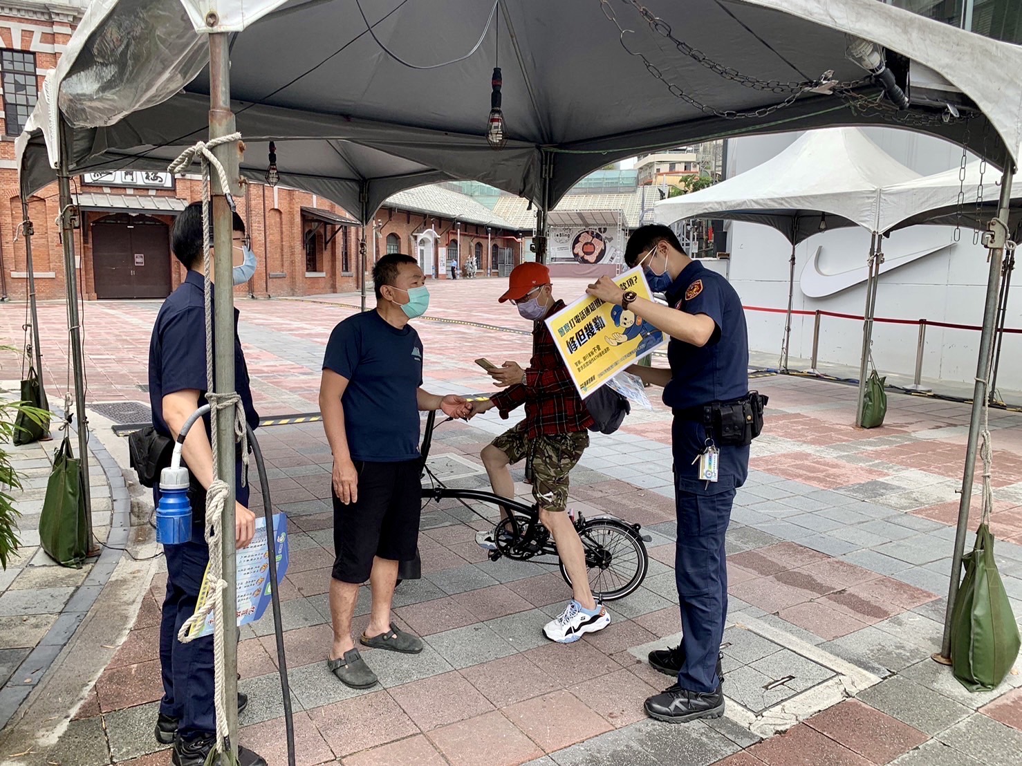 臺北市保安警察大隊員警手持宣導海報,以標語提醒民眾,小心防疫期間常見的簡訊詐騙。