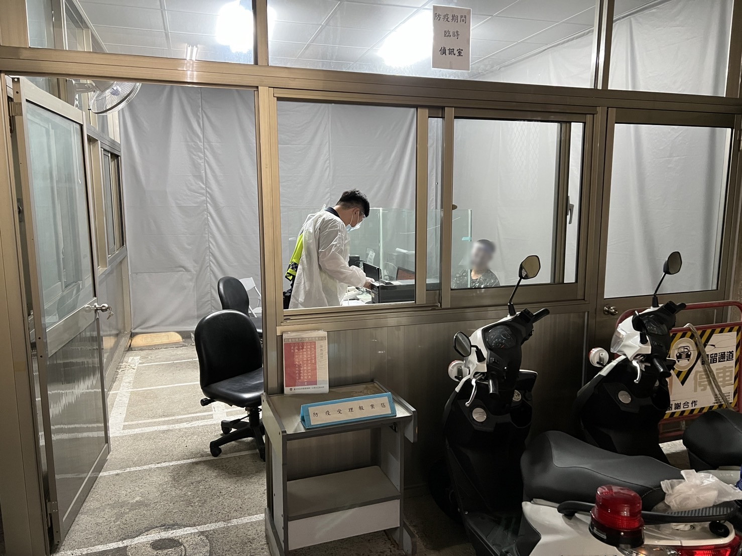 圖片說明:警員穿著全套防護裝備於戶外隔離偵詢室偵訊犯嫌。(記者謝榮浤翻攝)