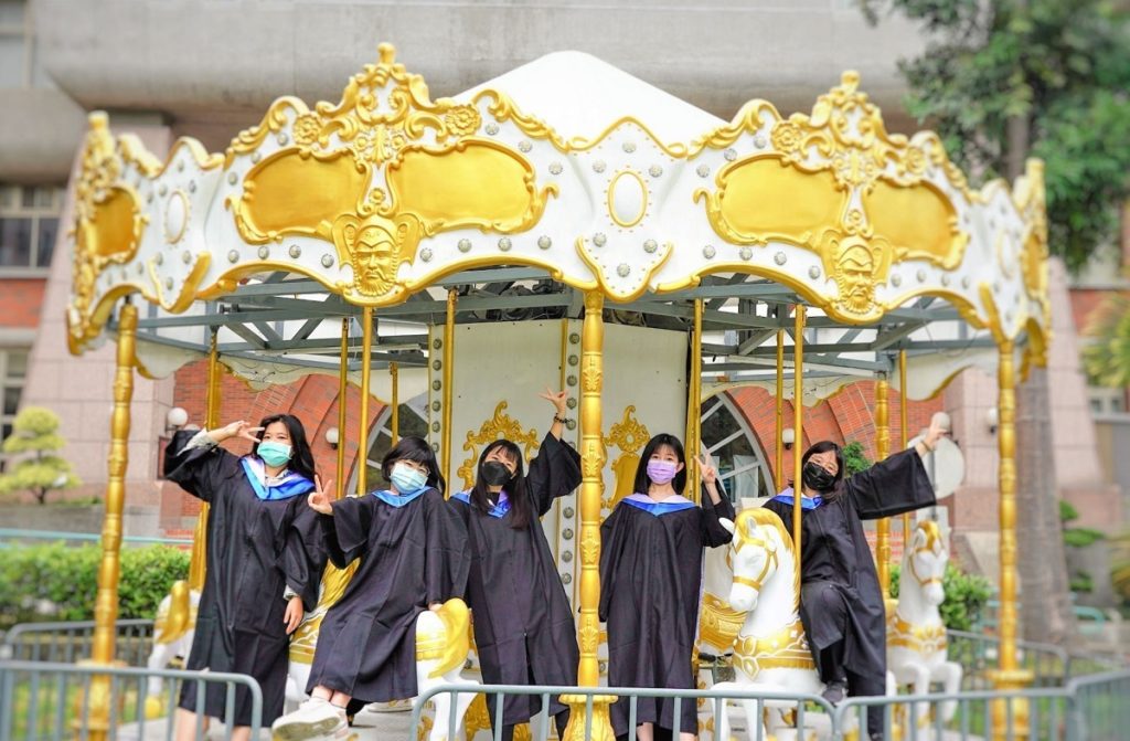 校園布置夢幻旋轉木馬,讓朝陽科大變身為畢業生的樂園,還有人排隊搭乘,童趣十足。(圖/朝陽科大提供)