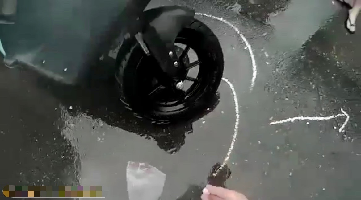 圖片說明:因大雨狂下且車流湧現,保大員警見狀立刻在車禍現場路面,用白色粉筆劃註車輛交通事故記號及拍攝現場照片。(記者宋紹誠翻攝)