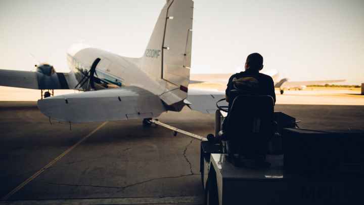 baggage carrier on airfield with plane