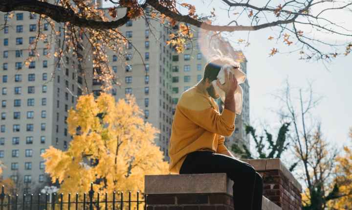 faceless man wiping sweat from face and sitting on fence