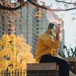 faceless man wiping sweat from face and sitting on fence