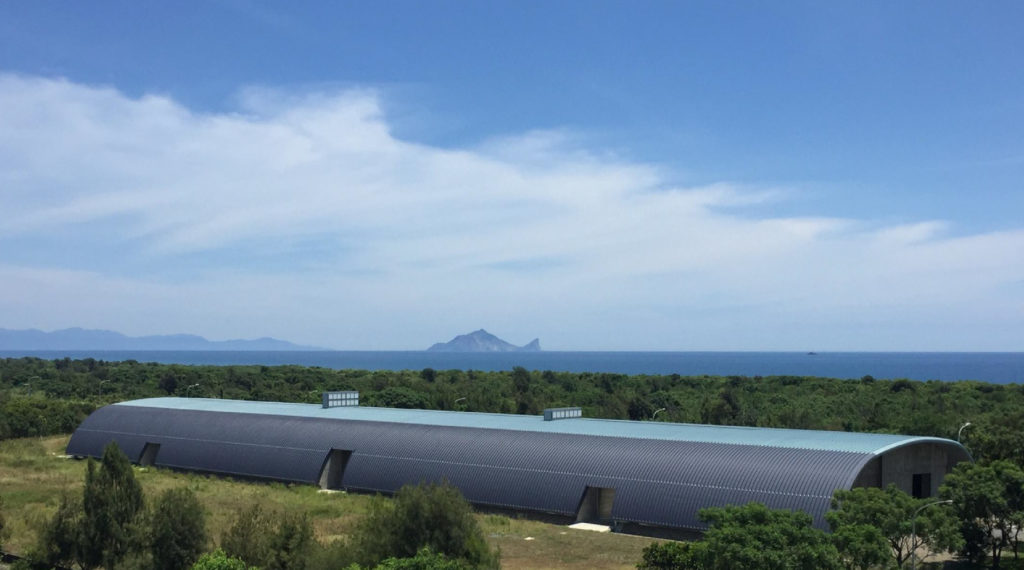 劉黃謝堯|利澤飛灰暫存場 - 時間中的地理尺度行動 倉儲基地位於利澤沙丘,是飛灰殘餘,透過穩定固化堆放在沙丘背後的儲存場。將露天開放式進化為倉儲披覆式,降低淋雨後汙染環境的可能性。