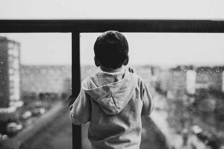 backview of sad child waiting on a glass window