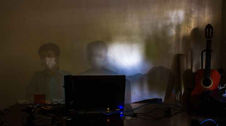 employee sitting near laptop in medical mask during concert