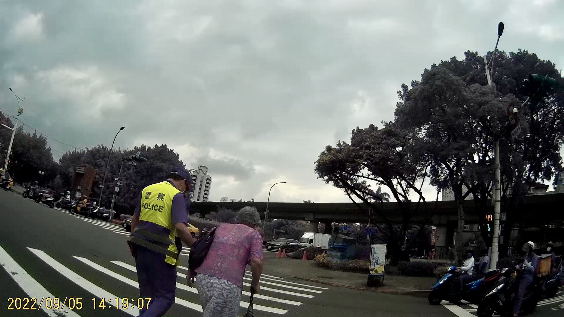 圖:臺北市保安警察大隊吳中隊長迅速下車攙扶老婦人,等行人號誌綠燈後陪同過馬路至安全處。