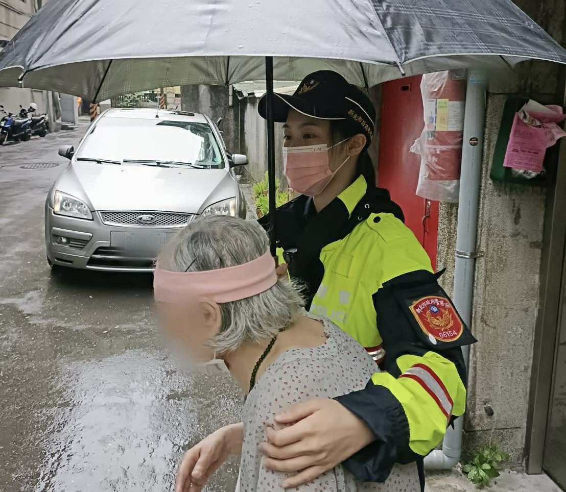 圖片說明:中和警撐傘帶老婦回家。(記者徐煜勝翻攝)