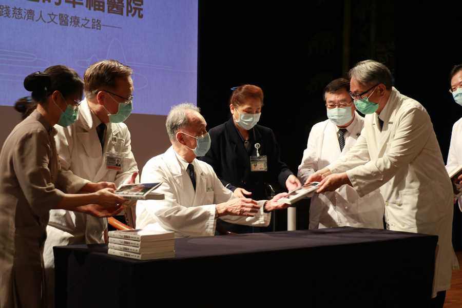 王人澍(右)、蔡顯揚(右二)兩位臺中慈院副院長,從執行長手中拿到有簽名章的新書。