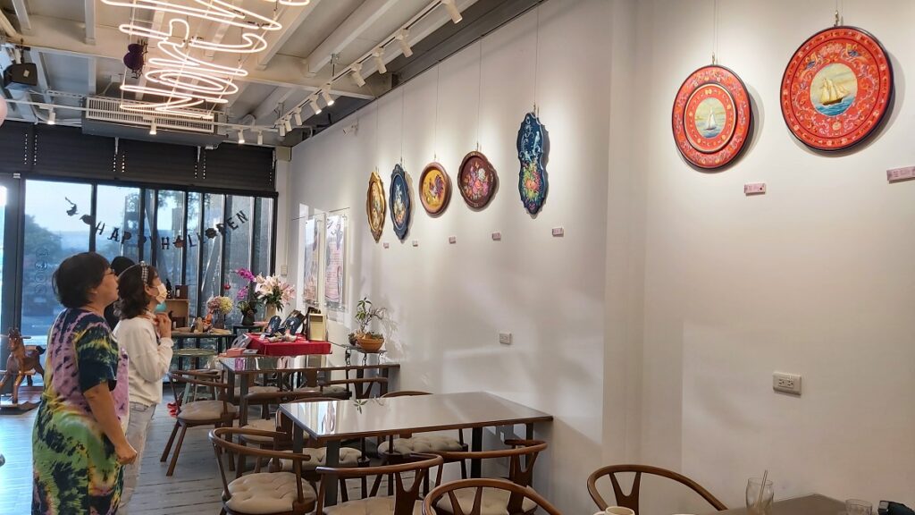 藝術家李芸溱為前來喝咖啡的客人解說她的作品。(圖/陳惠玲攝影)