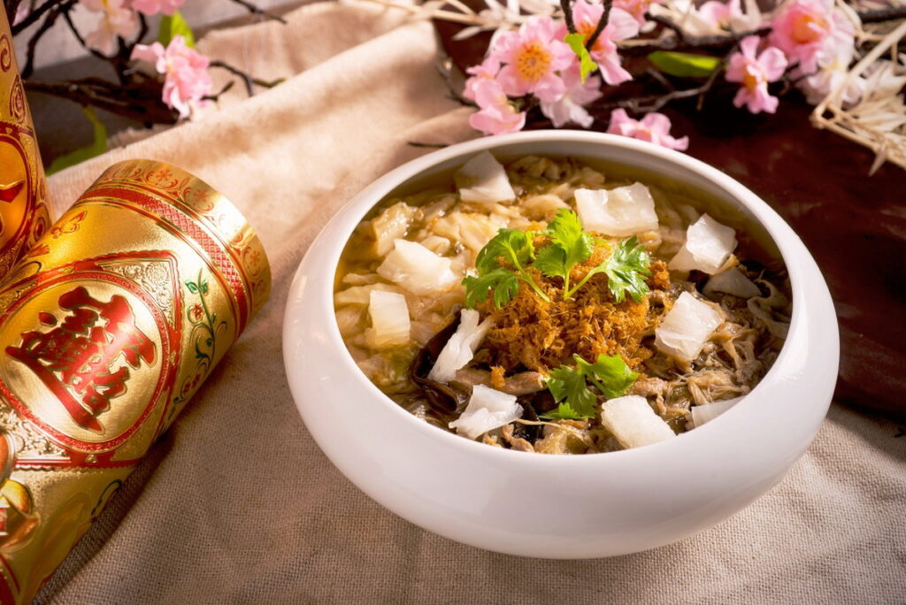 「六福客棧 極品花椒滷白菜」以鮮甜大白菜燉煮出清甜爽口的湯頭,搭配特製五香肉條、魚皮、炸豬皮、香菇,拌入酥脆蛋酥、干貝絲及花膠,一次吃到山珍海味及蔬菜鮮甜口味(圖_六福旅遊集團提供)