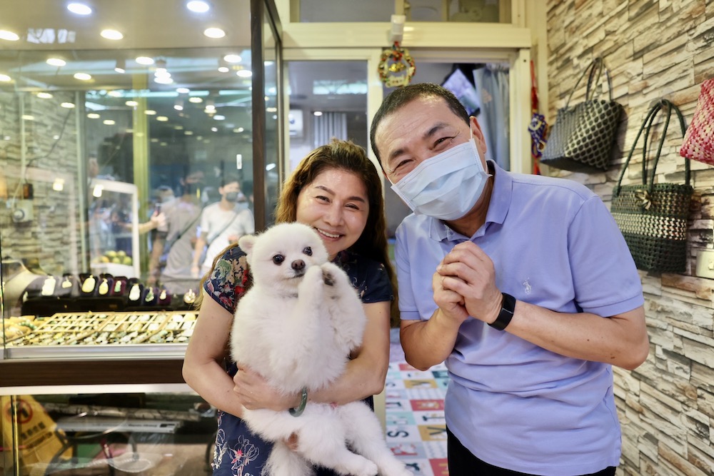 熱情攤商抱著愛犬「樂樂」與新北市長侯友宜合影，樂樂模仿他的拜票手勢。