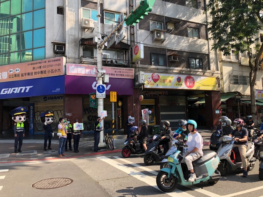 圖：藉機車騎士停等紅燈宣導科技執法即將啟用，務必遵守交通規以免荷包失血。