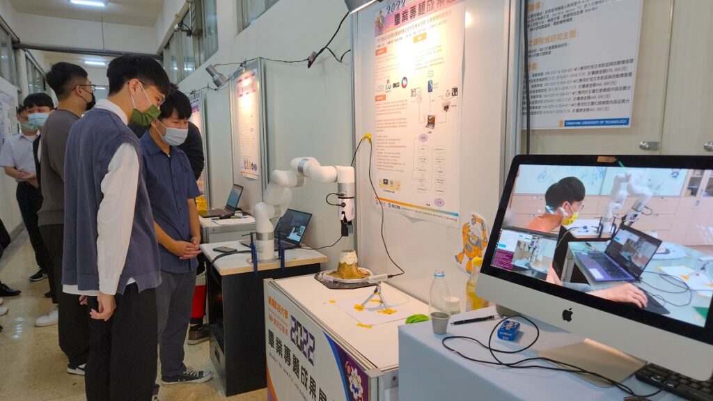 資工系學生王睿、王崇祐現場利用聲控進行機械手臂實體操作。(圖/陳惠玲攝影)
