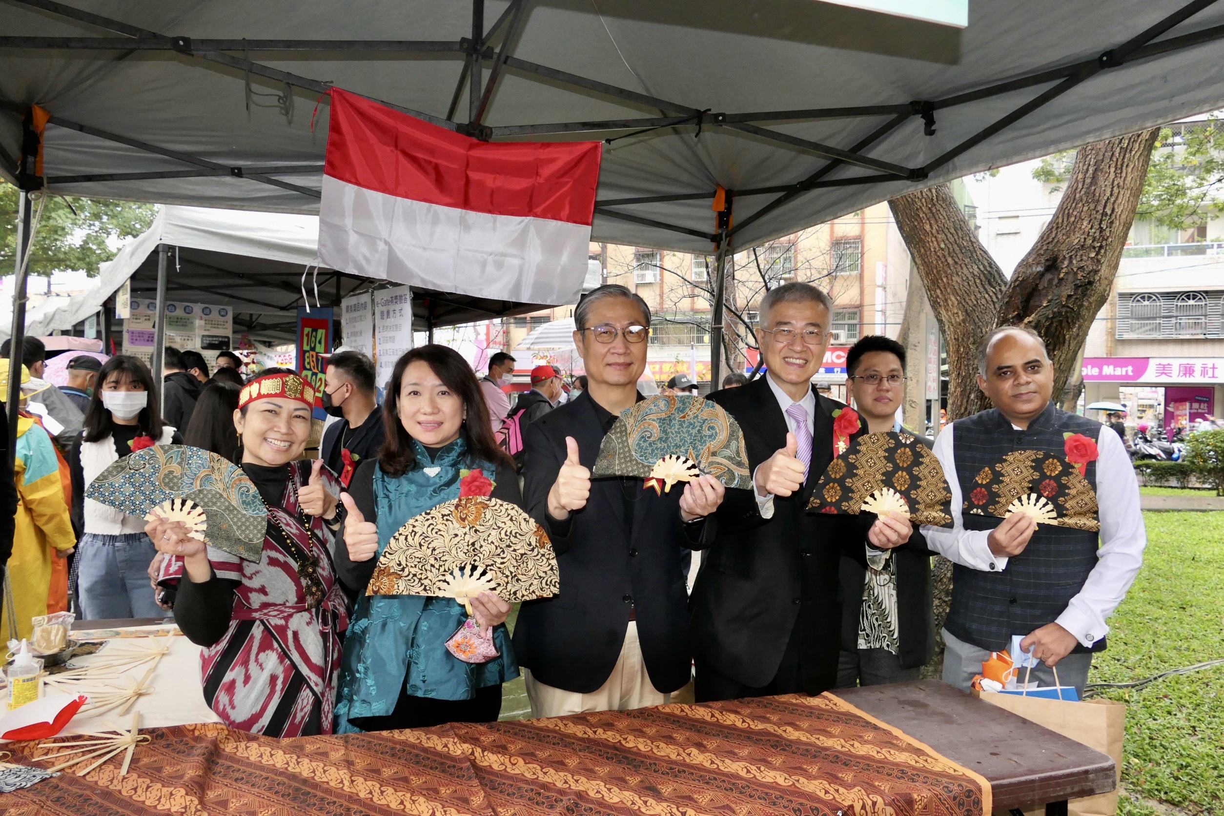移民署署長鐘景琨(左三)、桃園市副市長李憲明(右三)、立委羅美玲(左二)及印尼代表處郭進來專員一同逛桃園新市集攤位,體驗手作印尼蠟染扇子。(記者馬治薇攝)