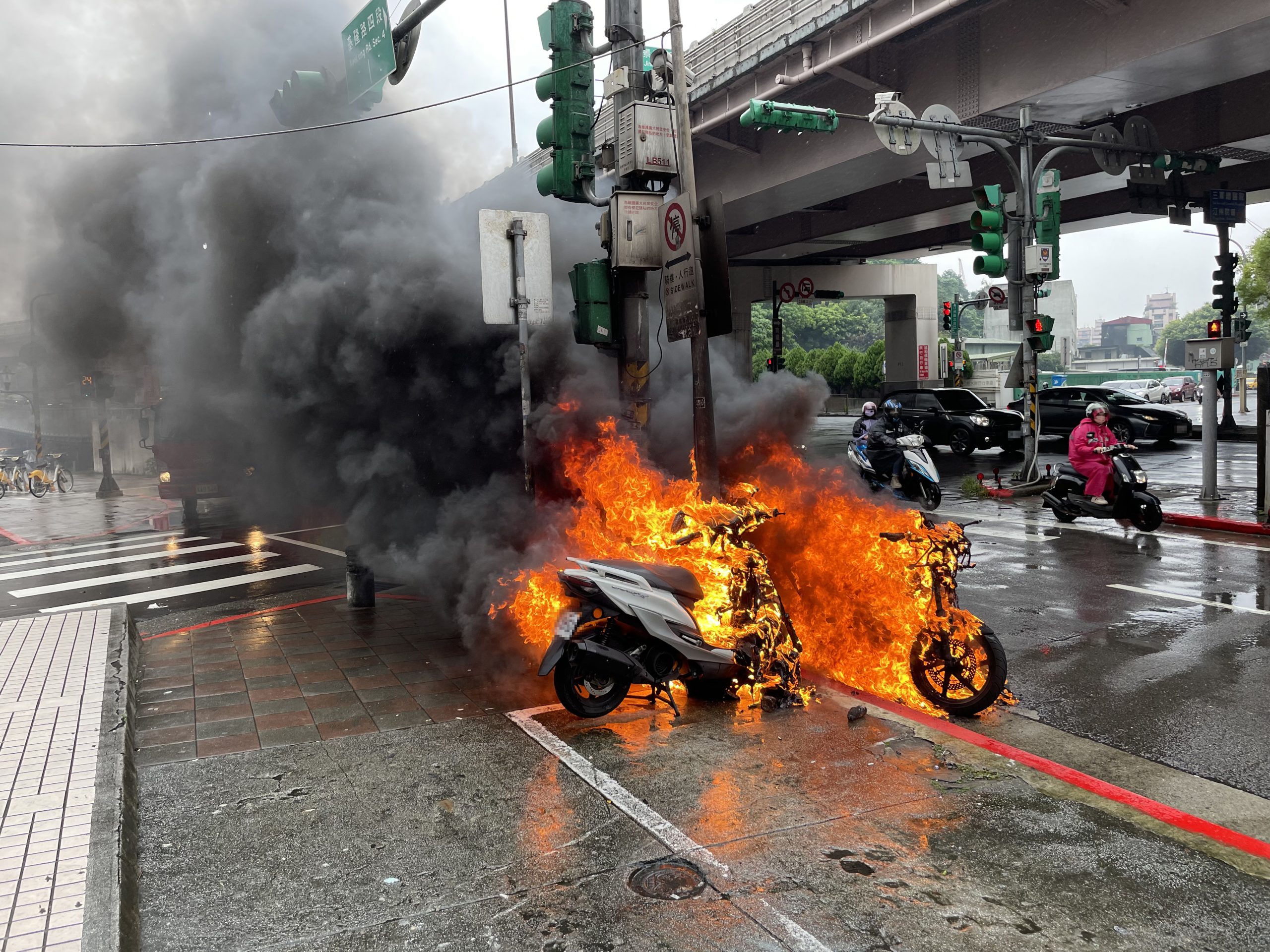 臺北市保安警察大隊員警趕赴起火點,發現燃燒中的兩輛機車與一輛自行車已陷入火海。(記者宋紹誠翻攝)