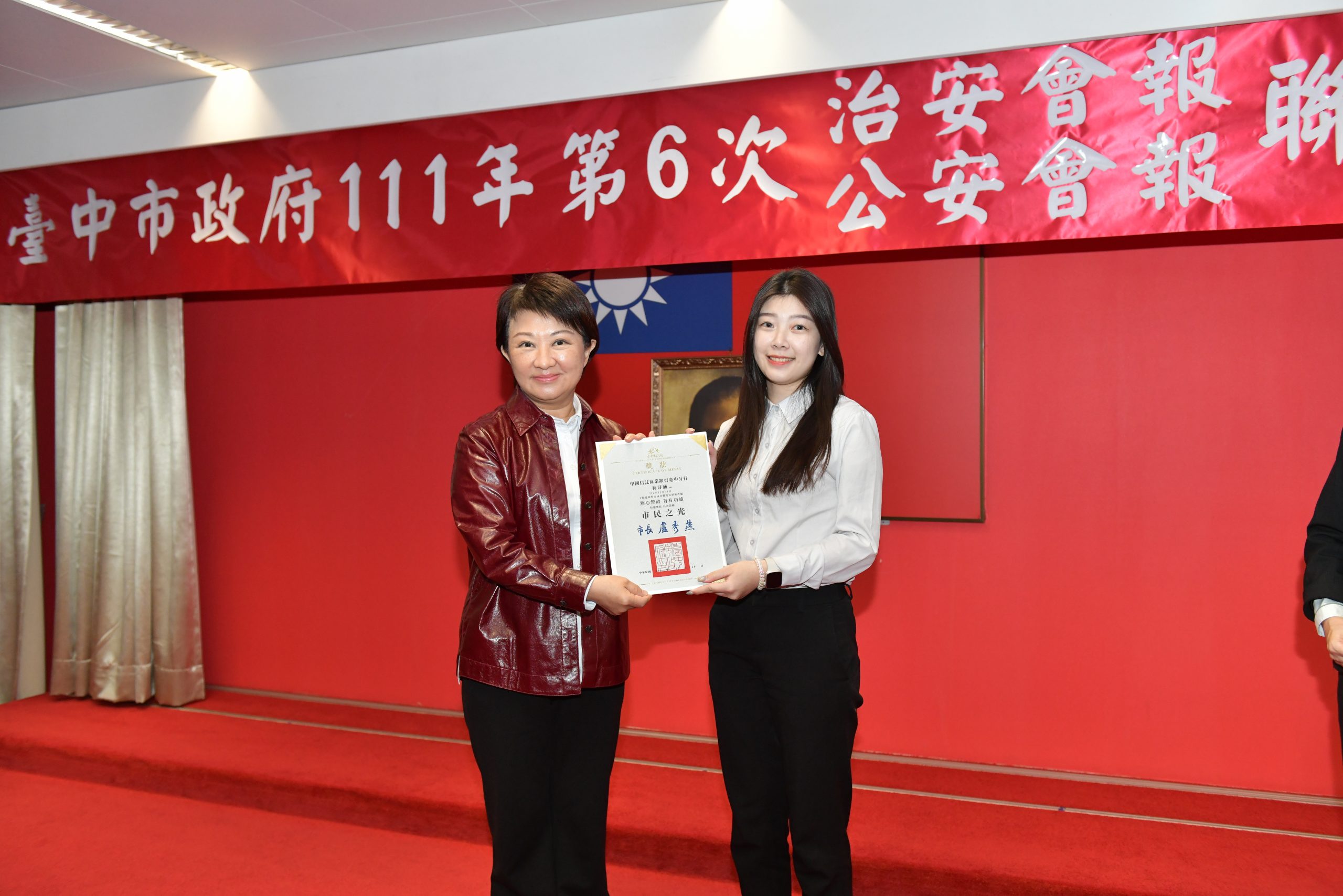 臺中市政府召開治安會報市長盧秀燕親自頒獎,表揚9名成功攔阻民眾避免被騙金額達200萬元的行員。(圖/林㤈輝翻攝)