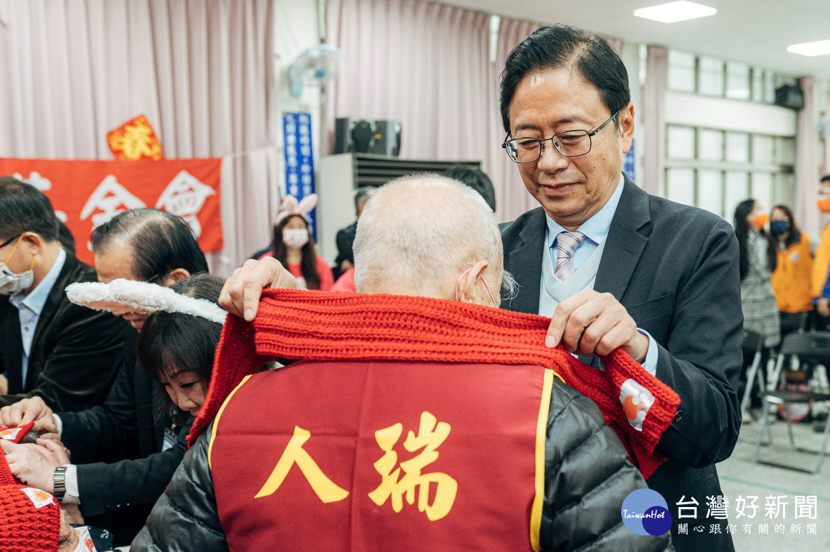 桃園市長張善政出席年菜公益募集活動,為長者圍上禦寒的圍巾。
