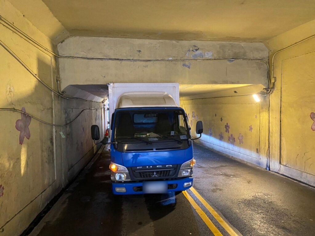 自小貨車未注意地下道限高卡在地下道,警察協助輪胎洩氣,助自小貨車順利脫困。