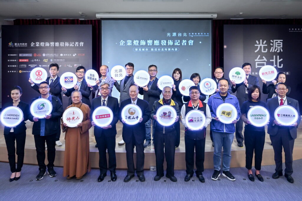 台北市政府張溫德副秘書長(中間排右六)、交通部觀光局國民旅遊組徐佩鈴專門委員(中間排右五)、台北市政府觀光傳播局陳淑慧局長(中間排右四)、台北市政府產業發展局陳俊安局長(中間排左四)、台北市政府民政局陳永德局長(中間排左三)及各家企業與民間團體代表手持LOGO牌發亮，象徵一同聚光城市、點亮台北！