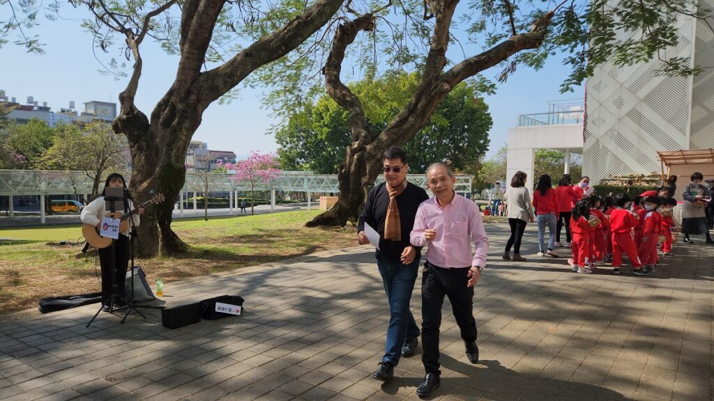 工藝中心全園區於大年二至初八,推出「樂音好禮」!其中在鳳凰樹下有街頭音樂演出。記者會後,左畫面街頭藝人現場吉他彈唱。(圖/陳惠玲攝影)