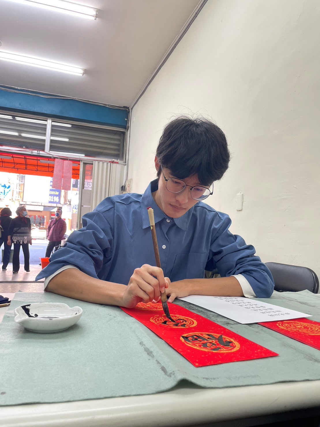 臺中北區賴厝里辦公室及賴厝社區發展協會共同主辦「賴厝傳統年糕技藝傳承暨新春揮毫」活動,高雄師範大學陳平同學義助揮毫。(圖/賴厝社區發展協會提供)