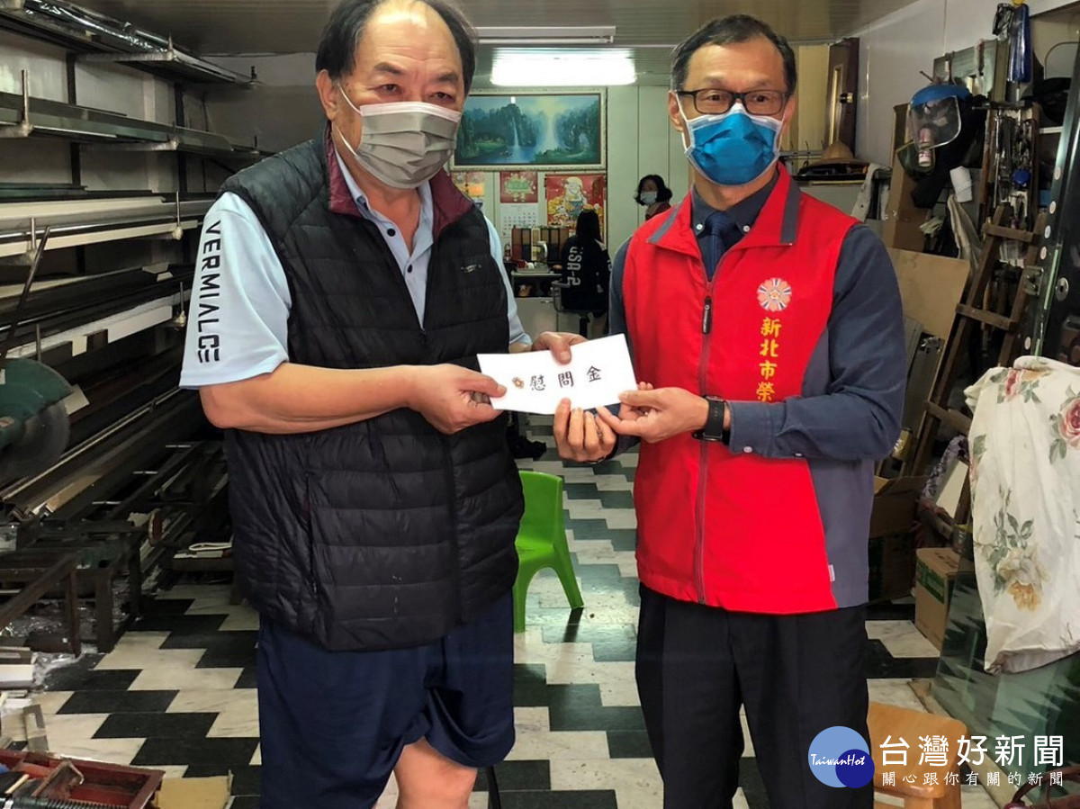 處長周興國(右)致贈慰問金予該大樓遭受波及的榮民唐先生(左),並關懷慰問