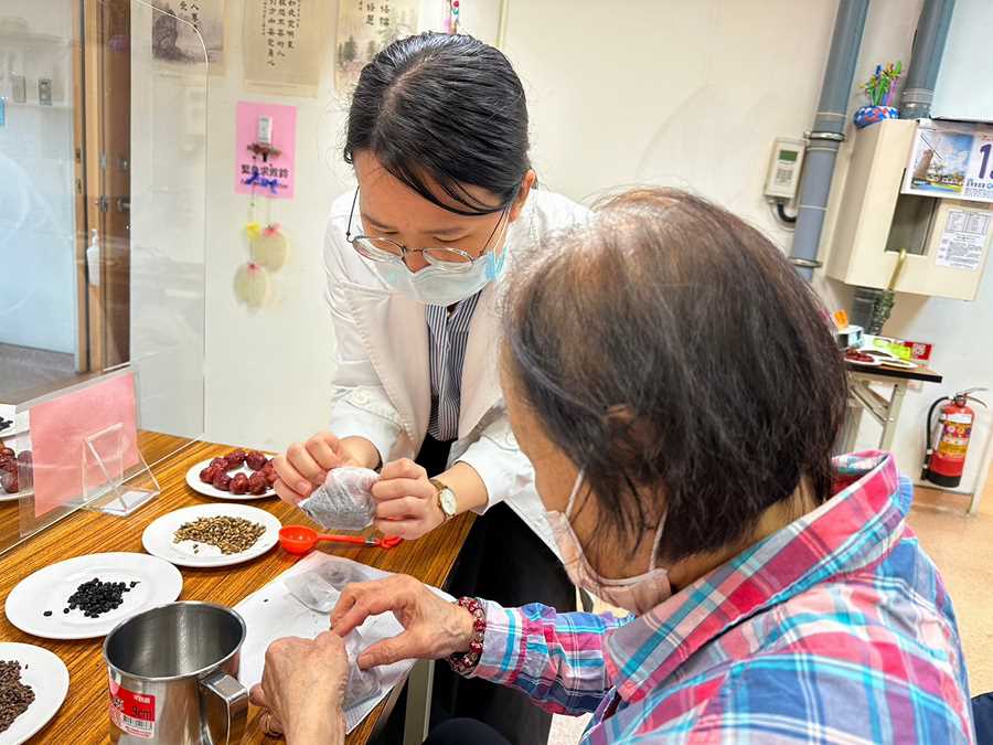 鄭宇真醫師(左)為學員長輩示範將藥材裝入茶袋中。