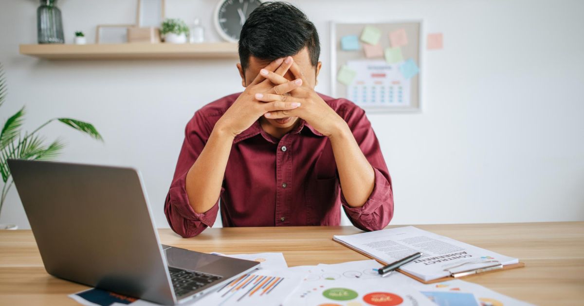 1200-man-working-with-laptop-paperwork-with-stress