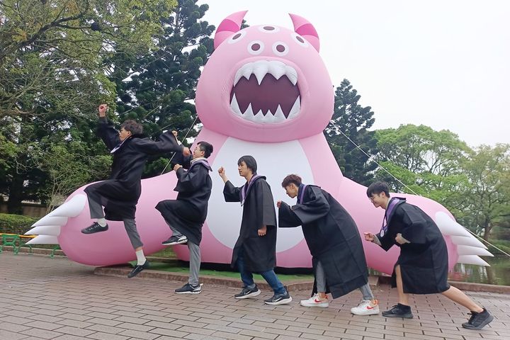 畢業生在外星獸氣球裝置前搞怪拍起人類進化史過程。 圖:六福村主題遊樂園/提供