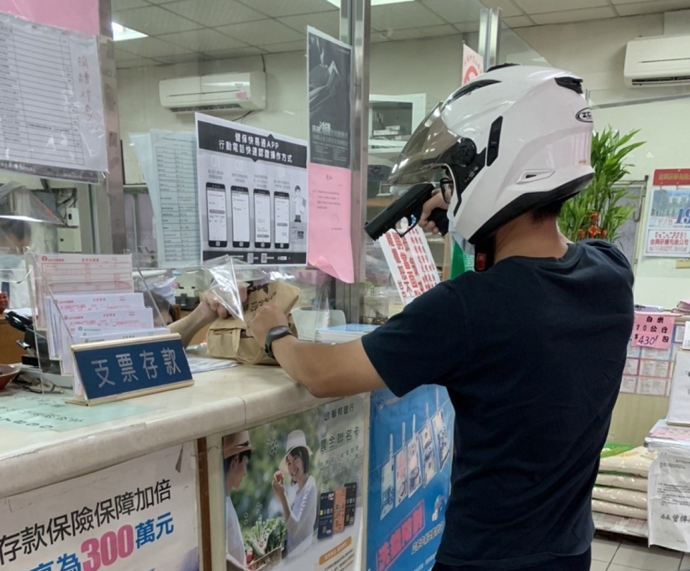 ▲圖說：扮演的搶匪持槍進入農會，喝令行員將現金放入紙袋 （圖／台中市政府提供）