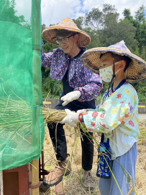 盧展猷行政副總經理(左)腳踩打穀機，讓小朋友體驗脫穀(圖：臺灣港務公司)