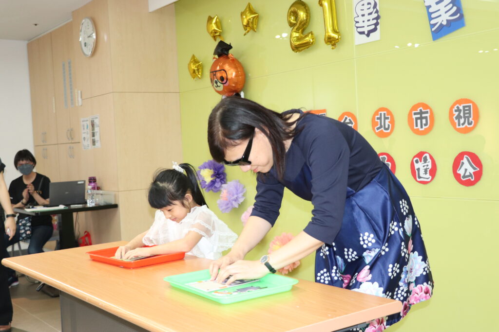 圖說:台北市教育局特教科科長官月蘭發(右)挑戰和畢業生代表比賽拼圖。