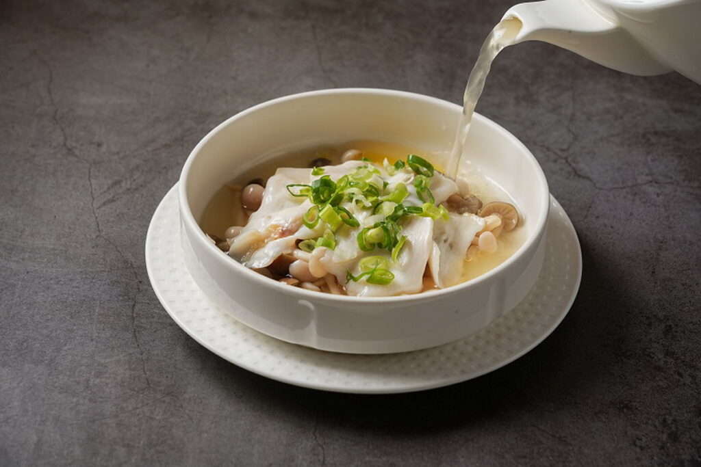 「過橋响螺片」以上等老母雞、金華火腿等食材扣燉48小時,選用墨西哥响螺中段軟嫩多汁部位切片,桌邊服務淋上濃郁滾燙的高湯。(圖/神旺潮品集.忠孝店提供)